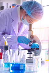 Young Asia  woman scientist working in laboratory.She is looking microscope.She is trying and research with red and blue test tube. Experiment , chemical Photo concept develop and medicine.