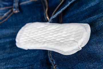 Woman hygiene protection, close-up panty liners on jeans background. Women's health. Feminine pads. Critical days. Discrete panty liner or pad for woman. Intimate hygiene. Daily panty liners.