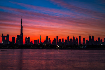 Mythical morning, sunrise or dusk in Dubai. Dawn over Burj Khalifa. Beautiful colored cloudy sky over Dubai downtown . Glow over buildings or skyscrapers