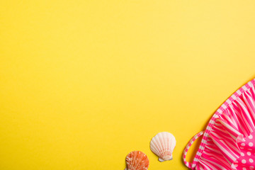 swimsuit and seashells on yellow background. copy space, top view