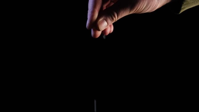 Hand sprinkles flake salt on black background in slow motion