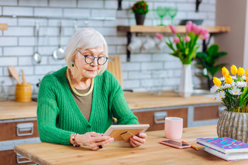 Nice-looking dame attentively looking at family portrait in frame