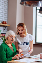 Charming volunteer explaining granny how to correctly fill in application