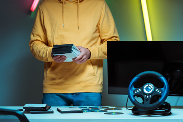 cropped view of man standing and holding compact disks with video games
