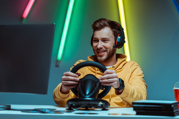 young adult and handsome man in headphones playing video game with steering wheel © LIGHTFIELD STUDIOS