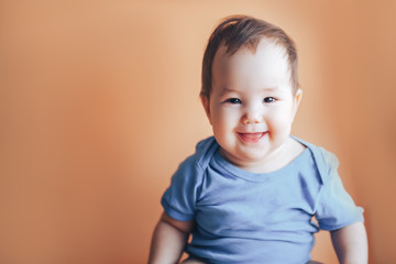 Beautiful small girl or boy with dark hair smiling on a bright orange background colour of 2019 with space for text happy smile look at camera