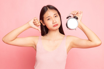 Young Asian woman thumbs down with a clock.