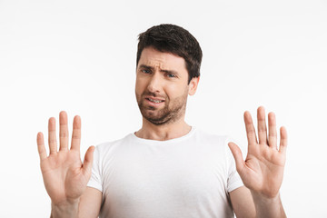 Image of displeased man 30s with bristle in casual t-shirt rejecting and doing stop gesture