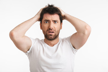 Image of muscular man 30s with bristle in casual t-shirt frowning and grabbing head