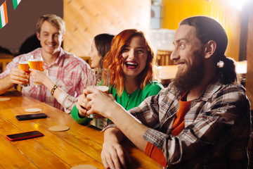 Beaming girlfriend clanging glass of beer with her boyfriend