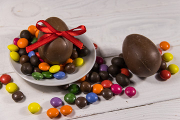 Easter composition with chocolate eggs on white wooden background