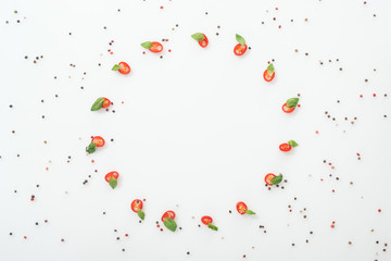 flat lay with spices and sliced chili peppers with basil leaves on white background with copy space