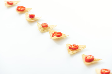 flat lay with tasty nachos and sliced chili peppers on white background with copy space