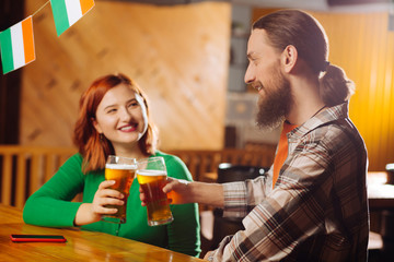 Bearded man drinking beer with his cheerful woman