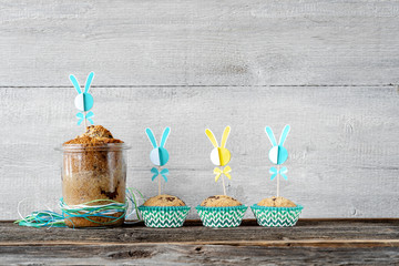 Osterkuchen im Glas und Muffins vor Holzwand