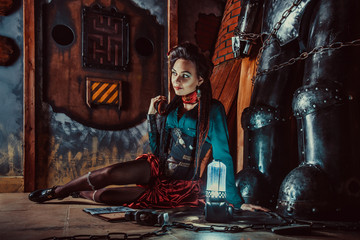 Sexy woman is relaxing with the book in the workshop. Big robot on the background.