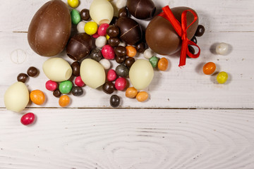 Easter composition with chocolate eggs on white wooden background