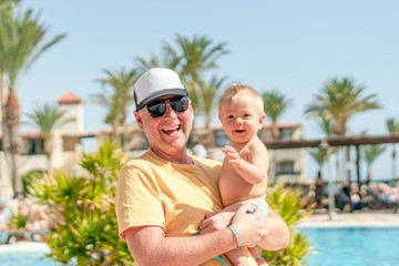Happy father holding cheerful son during tropical vacation