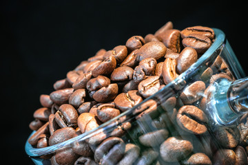 glass transparent cup with coffee beans inside close-up, in a low key