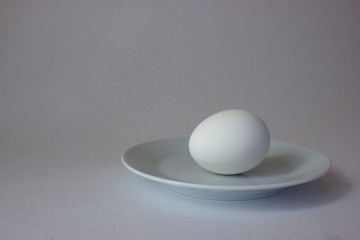 White chicken egg on plate