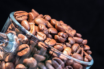 Obraz premium glass transparent cup with coffee beans inside close-up, in a low key