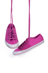 Magenta sneakers hang on laces isolated on a white