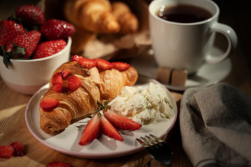 Breakfast concept with coffee cup, croissants, cream and fresh berries.
