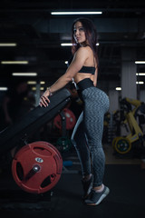 Obraz na płótnie Canvas Fitness girl posing in the gym, showing off her body and relaxing after a workout