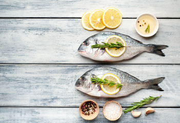 Two fresh raw Dorado fish with spices and olive oil on a wooden table.space for text 