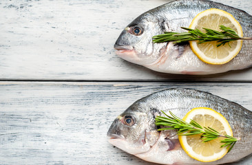 Two fresh raw Dorado fish with spices and olive oil on a wooden table.space for text 