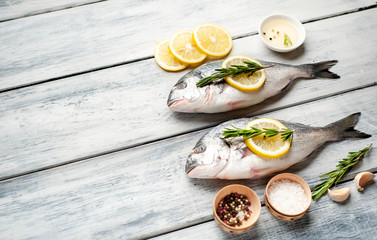 Two fresh raw Dorado fish with spices and olive oil on a wooden table.space for text 