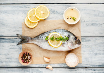 Dorado fish with spices and olive oil on a wooden table. 