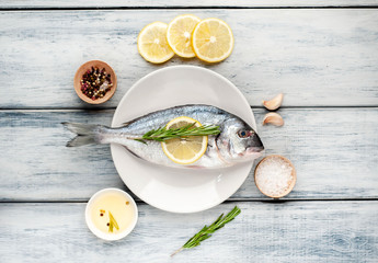 Fototapeta na wymiar Dorado fish in a plate with spices and olive oil on a wooden table