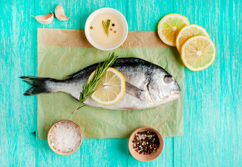 Dorado fish with spices and olive oil on a wooden table. 