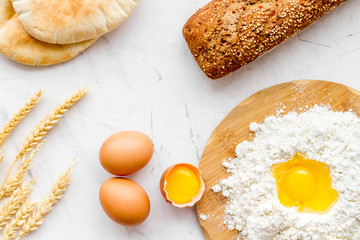 Make bread concept. Bread near wheat ears, flour and eggs on white background top view