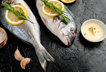 two fresh raw Dorado fish with spices and olive oil on a stone background.