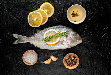 two fresh raw Dorado fish with spices and olive oil on a stone background.