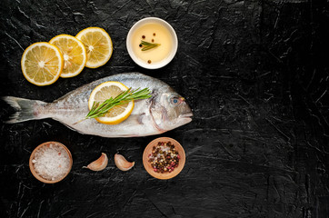 Fototapeta na wymiar two fresh raw Dorado fish with spices and olive oil on a stone background.