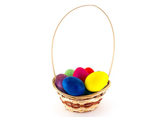 Colorfull Easter eggs in wicker basket isolated on white background
