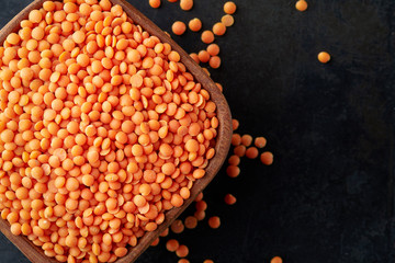 Raw uncooked red lentils (lens culinaris) in wooden bowl. Top view with copy space