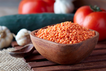 Raw uncooked red lentils (lens culinaris) in wooden bowl