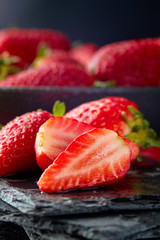 Fresh ripe organic strawberries in bowl on black rustic background
