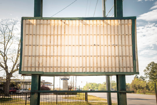 An old, dilapitated and empty changeable letter sign board on a street.