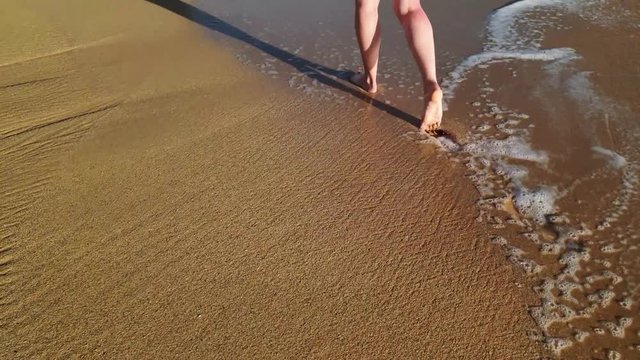 Beach travel - young girl walking on sandy beach leaving footprints in the sand, Hawaii, USA