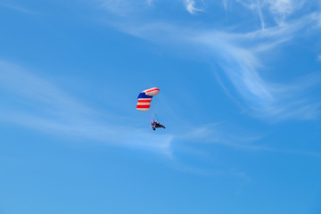 Pilot hang gliding on a blue sky background.