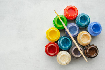 Colorful stained glass or oil, acrylic paints with paint brush  on gray background with copy space, top view.