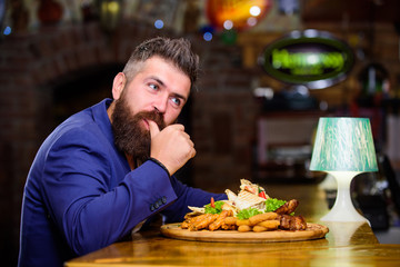 Hipster hungry eat pub fried food. Man received meal with fried potato fish sticks meat. High calorie snack. Enjoy meal. Cheat meal concept. Manager formal suit sit at bar counter. Delicious meal