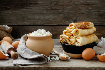 Frying pan of baked pancakes, ingredients and kitchenware for pancakes making on wooden kitchen...