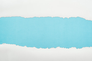 ripped white textured paper with copy space on blue polka dot background