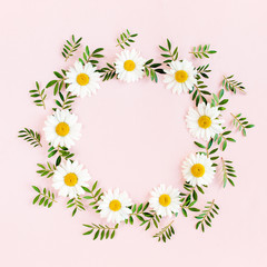 Naklejka na ściany i meble Round frame, wreath made of chamomiles, petals, leaves on beige background. Flat lay, top view
